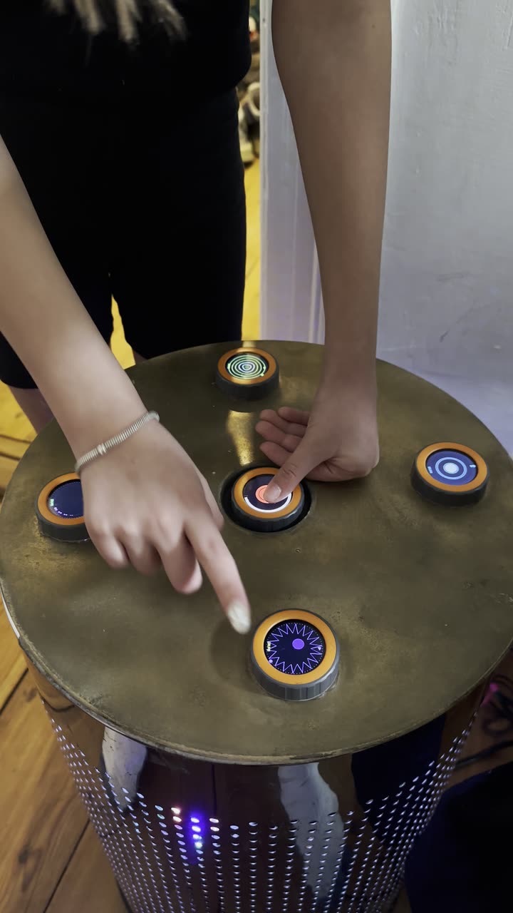 One person plays two discs of the finished TAMBUM table at once with both hands, the discs are lit
